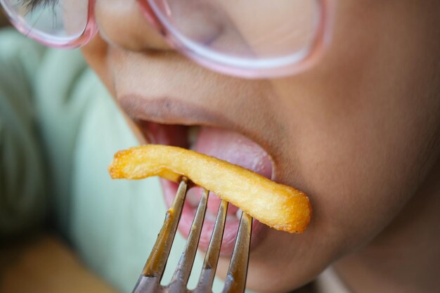 Photo un enfant mangeant des frites de près.