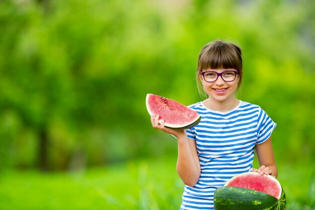 Enfant mangeant de la pastèque Pré adolescente dans le jardin tenant une tranche de melon d'eau happy girl kid ea...