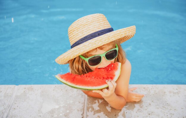 Enfant mangeant de la pastèque près de la piscine pendant les vacances d'été les enfants mangent des fruits en bonne santé à l'extérieur fo