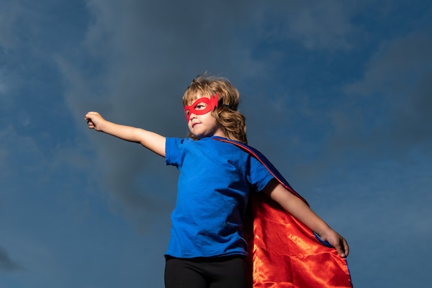 Enfant en manteau de super homme. Garçon jouant au super-héros. Concept gagnant du succès et des enfants.