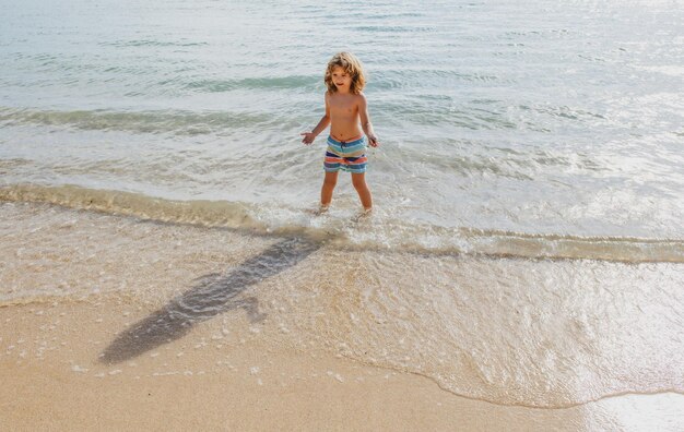 Enfant marchant sur la plage d'été garçon jouant sur la plage pendant les vacances d'été