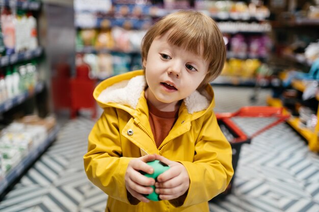 Un enfant sur le marché avec un chariot d'épicerie achète une balle