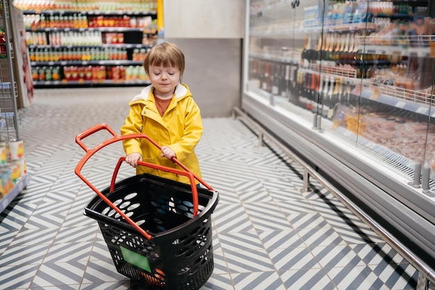 Enfant sur le marché avec un chariot d'épicerie portant une veste jaune et un jean