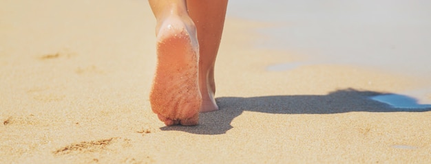 L'enfant marche le long de la plage en laissant des traces de pas dans le sable.