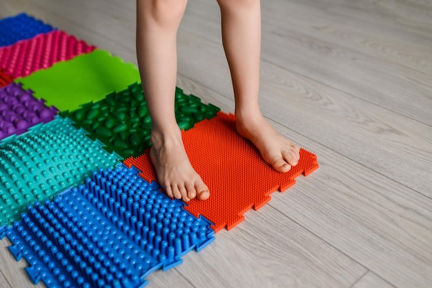 L'enfant marche sur un tapis de pied orthopédique de massage Tapis de massage de dureté et de texture différentes