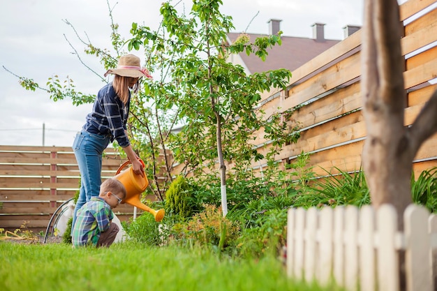 Enfant et mère arrosoir arrosant un jardin dans l'arrière-cour