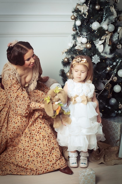 Enfant Avec Mère Recevant Près D'arbre De Noël.