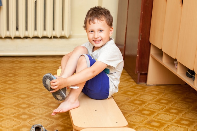 L'enfant met des chaussures à la maternelle