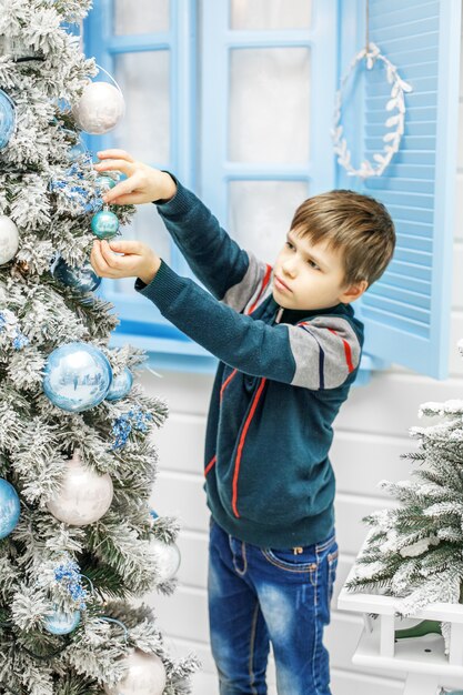 L'enfant met des ornements sur le sapin