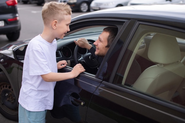 Un enfant mignon accompagne un père heureux au travail père est assis dans la voiture donner cinq