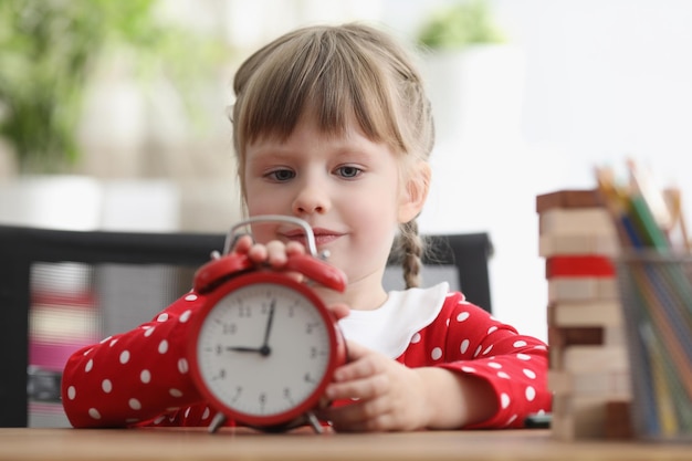 Un enfant mignon apprend à comprendre le temps et à jouer avec une horloge rétro rouge