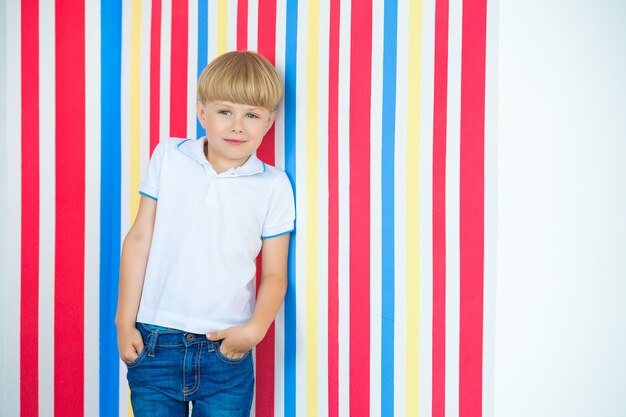 Enfant mignon bouchent portrait sur coloré. Adorable petit garçon debout près du mur.