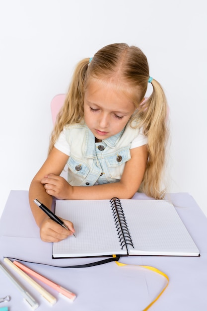 Enfant mignon fait ses devoirs sur fond blanc.