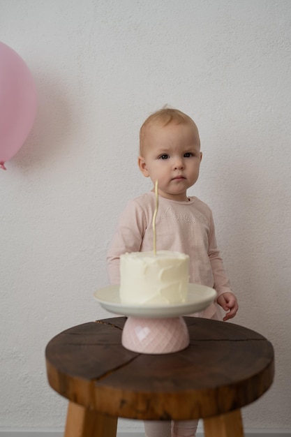 Un enfant mignon fête son anniversaire avec un gâteau contre un mur blanc une petite fille en rose en est une