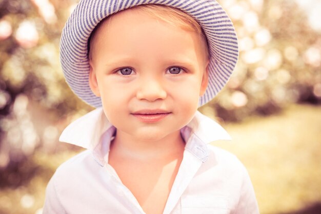 Enfant mignon sur l'herbe verte dans le parc d'été visage de bébé gros plan drôle petit garçon enfant gros plan portrai