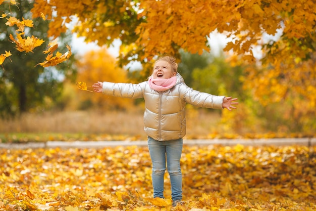 Enfant mignon jouant avec les feuilles d'automne