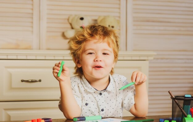 Enfant mignon jouant avec des jouets dans la salle de jeux Portrait d'enfant caucasien Enfant jouant avec des blocs colorés grimace