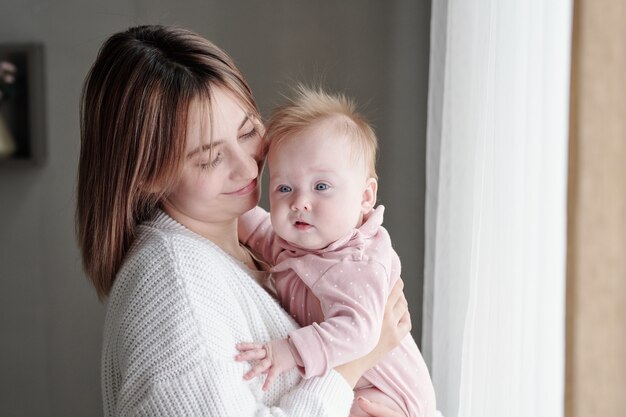 Enfant mignon sur les mains de sa jeune mère heureuse