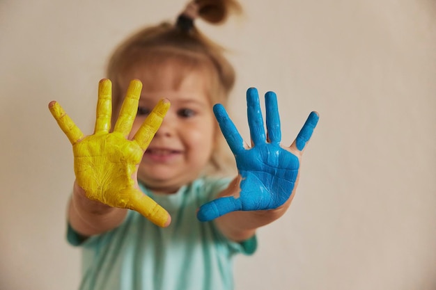 Un enfant mignon peint ses mains aux couleurs du drapeau ukrainien