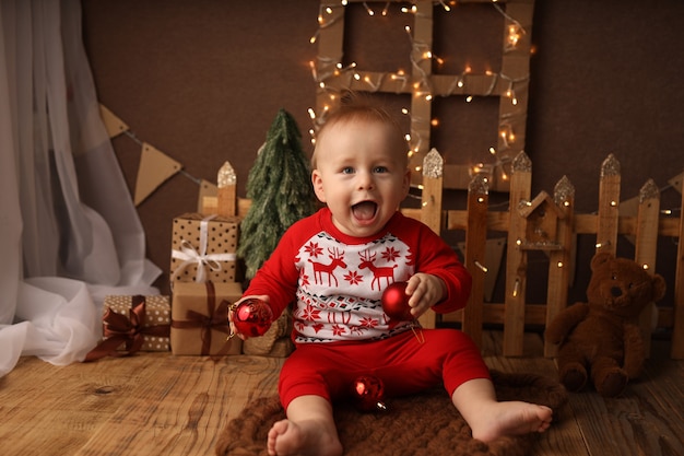 Un enfant mignon en pyjama du Nouvel An sort des boules de Noël d'un sac avec des cadeaux