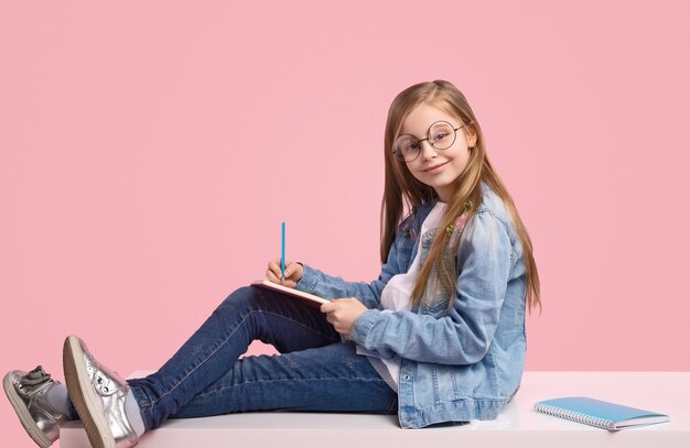 Enfant mignon en tenue à la mode pensant faire ses devoirs