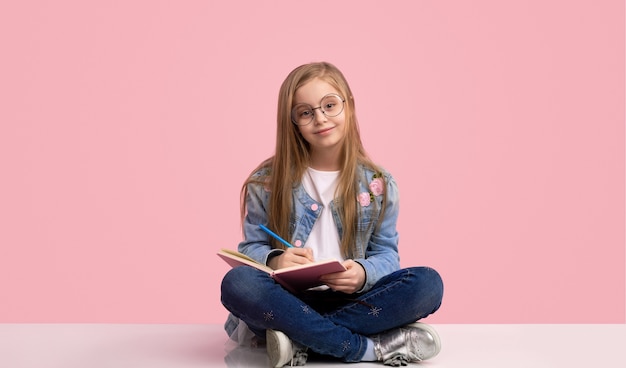 Enfant mignon en tenue à la mode pensant faire ses devoirs