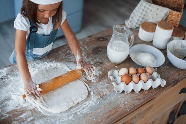 Enfant mignon en uniforme de chef blanc préparant la nourriture dans la cuisine.