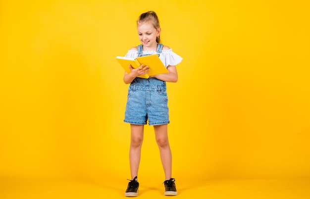 Un enfant mignon va lire les informations du livre de retour à l'école