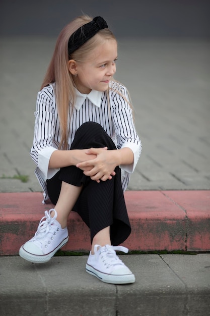 Un enfant en milieu urbain Une fille d'âge préscolaire est assise sur les marches