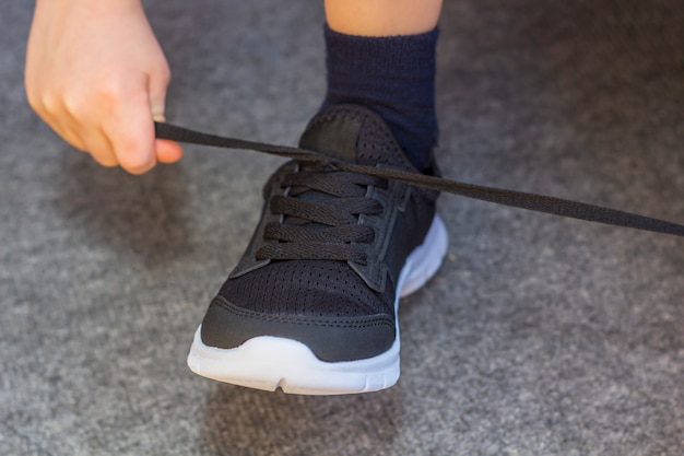 L'enfant a mis une paire de baskets. Jambes de jeune garçon en baskets noires de mode textile. Tenue décontractée et mode de rue pour enfants. Fermer