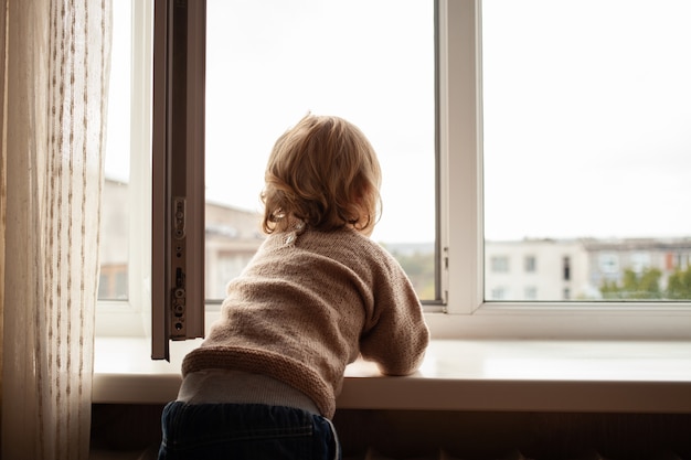 L'enfant monte à la fenêtre, la fille sur le rebord de la fenêtre repose sur le filet