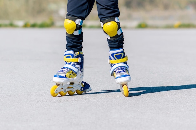 Un enfant monte des patins à roulettes bleus, jaunes et blancs