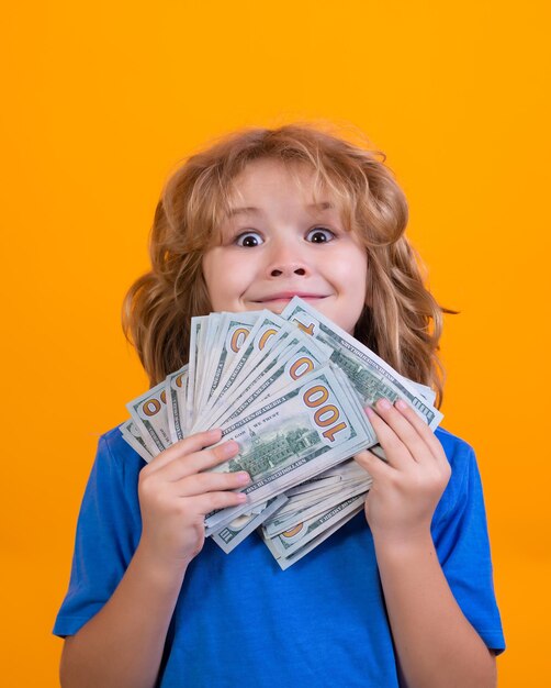 Enfant montrant des billets d'un dollar d'argent debout rêveur de riches sur fond de studio isolé