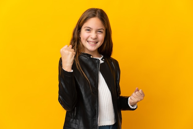 Enfant sur mur jaune isolé célébrant une victoire