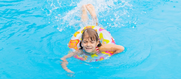 L'enfant nage dans la piscine en été