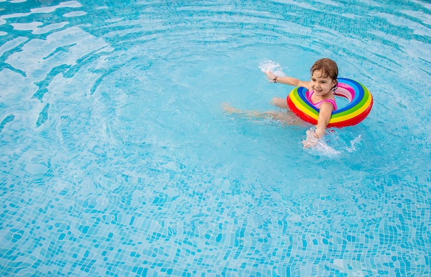 Un enfant nage dans une piscine avec un gilet de sauvetage.