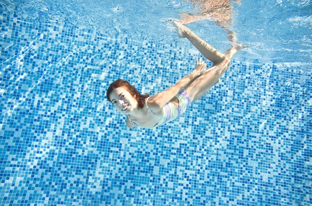 L'enfant nage dans la piscine sous l'eau une fille active heureuse saute des plongées et s'amuse sous l'eau