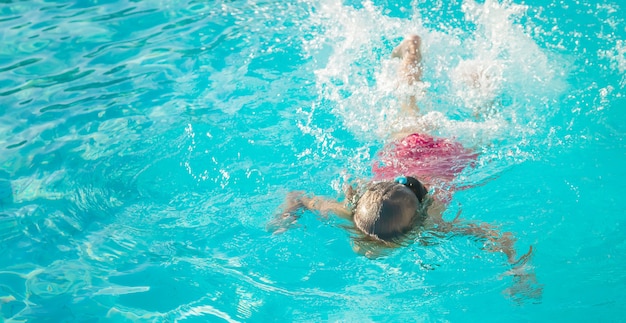 L'enfant nage et plonge dans la piscine.