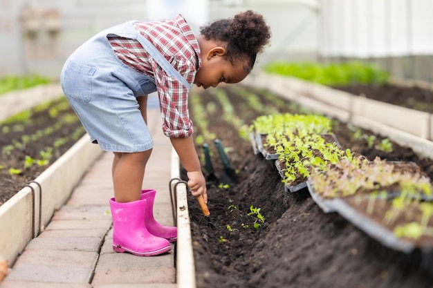 Photo enfant noir africain jouant à planter l'arbre vert jardinage dans la ferme agricole les enfants aiment le concept de la nature