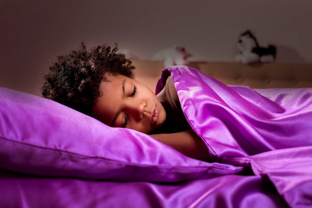 Enfant noir dormant la nuit. Minuit dans la chambre d'un garçon afro. L'obscurité a amené le silence. Fin de la journée.