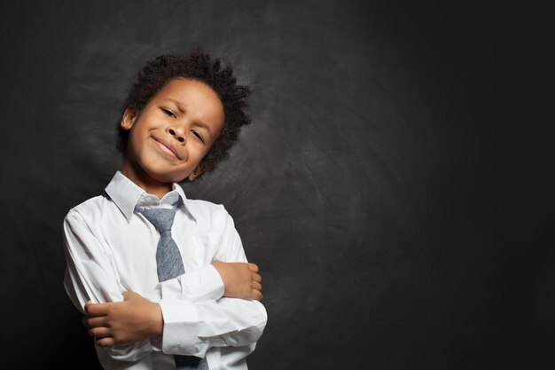 Un enfant noir intelligent et drôle en chemise blanche et cravate sur fond noir