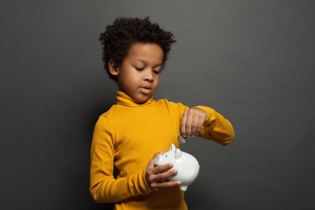 Photo un enfant noir met une pièce d'euro dans sa poche.