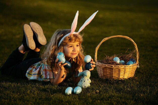 Enfant avec des oeufs de pâques dans le panier garçon en plein air allongé sur l'herbe dans le parc chasse aux oeufs de pâques fynny kids port