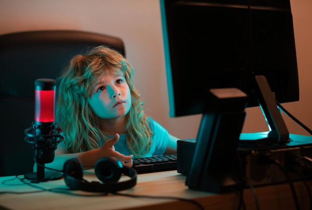 Enfant avec ordinateur pc la nuit un joli enfant apprend une leçon à l'aide d'un ordinateur de bureau à la maison