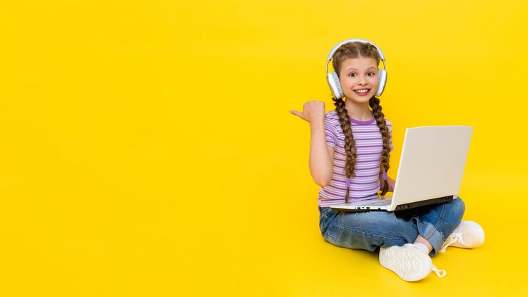 Un enfant avec un ordinateur portable Une petite fille est assise sur le sol et communique en ligne sur un ordinateur portable portant des écouteurs Communication Internet pour les enfants Espace de copie de fond isolé jaune