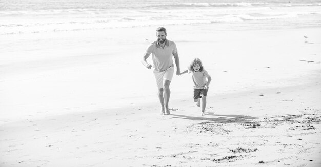 Enfant et papa courant sur la plage en vacances d'été ensemble vacances