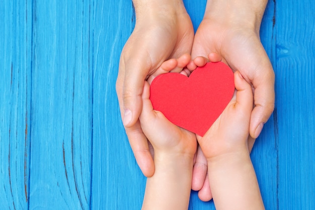 Enfant et papa mains tenant coeur rouge