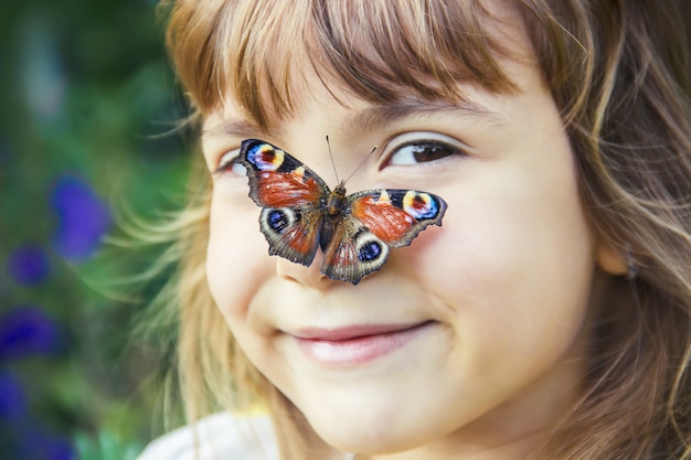 Enfant avec un papillon dans ses mains.