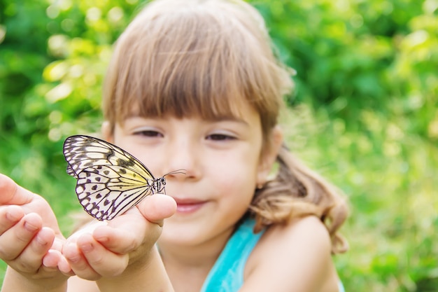 Enfant avec un papillon. Idée leuconoe. Mise au point sélective.