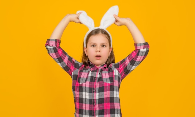 Enfant de pâques étonné dans des oreilles de lapin sur fond jaune